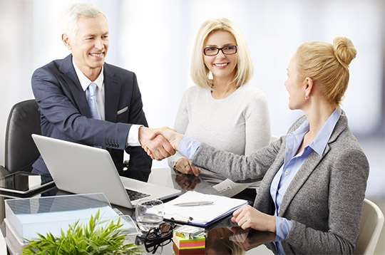 A man and woman shaking hands with an older gentleman.