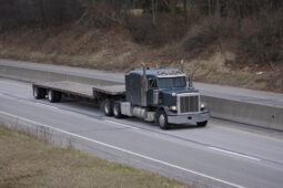 A semi truck is driving down the road.