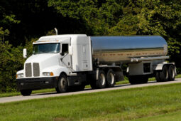 A white truck is driving down the road